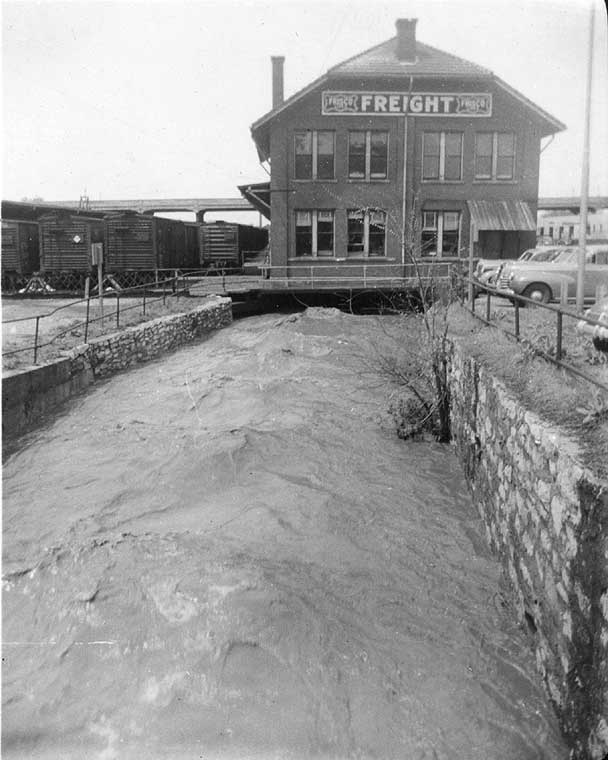 greyscale photo of depot over creek