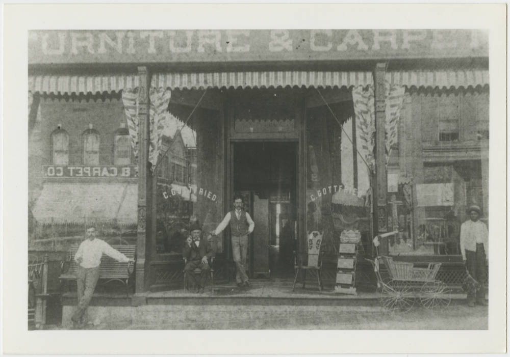 Greyscale image of men in front of a shop