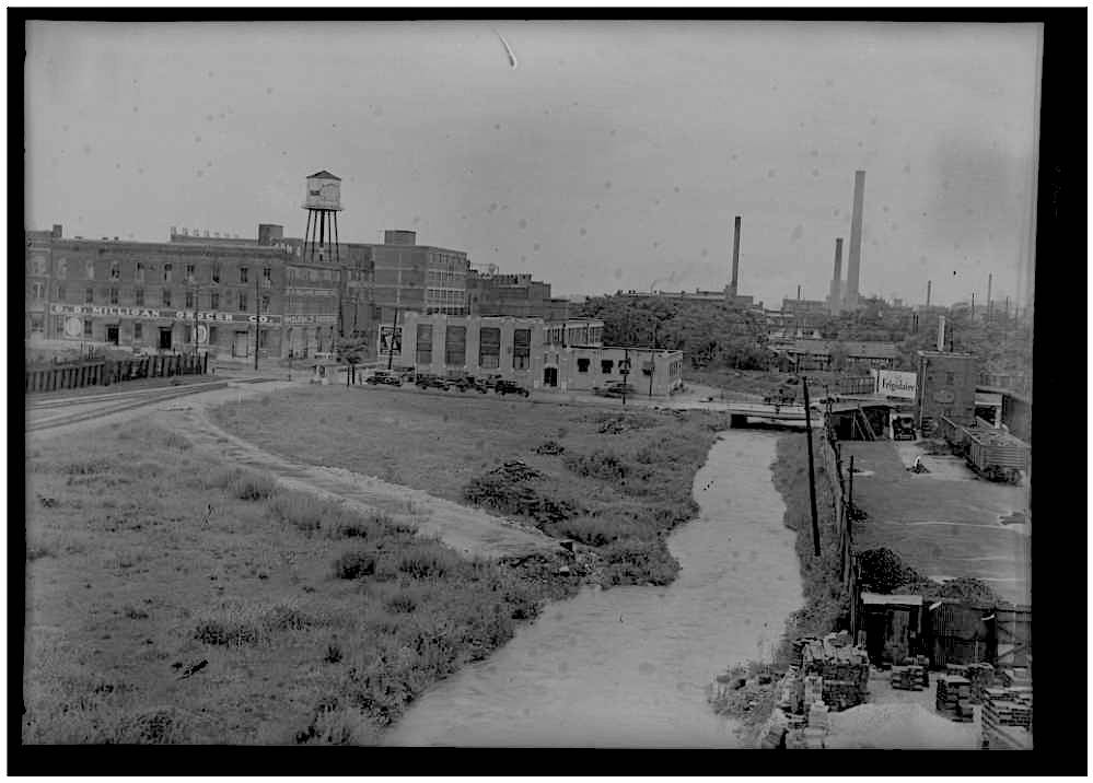 greyscale photo of creek and cityscape